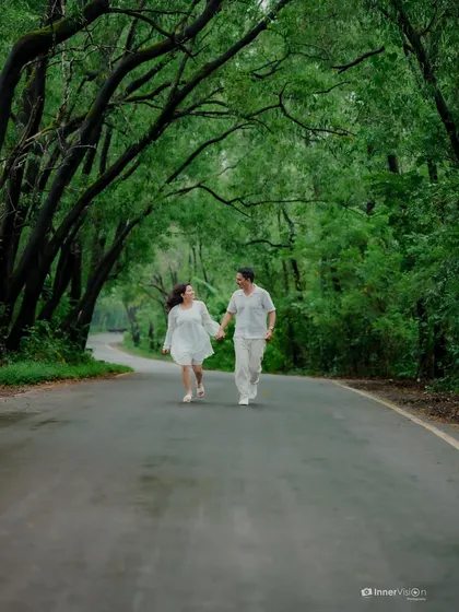 A romantic walk down a tree-lined country road. The canopy of green leaves creates a natural tunnel, making the scene feel intimate and secluded.