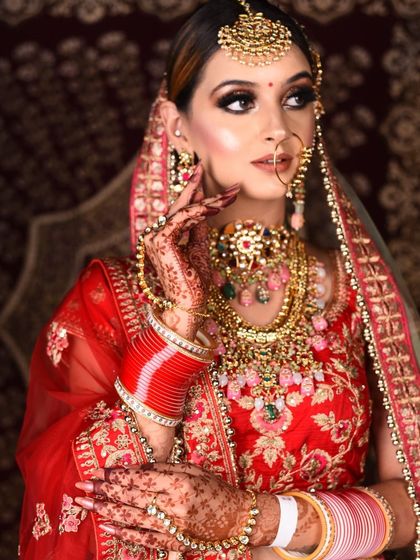 A closer look at the exquisite, multi-colored rental jewellery set against the red bridal lehenga. The details in the craftsmanship make this a truly special piece.