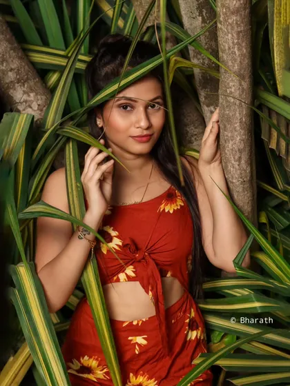 A portrait framed by leaves, creating a sense of being discovered in a tropical, natural setting.