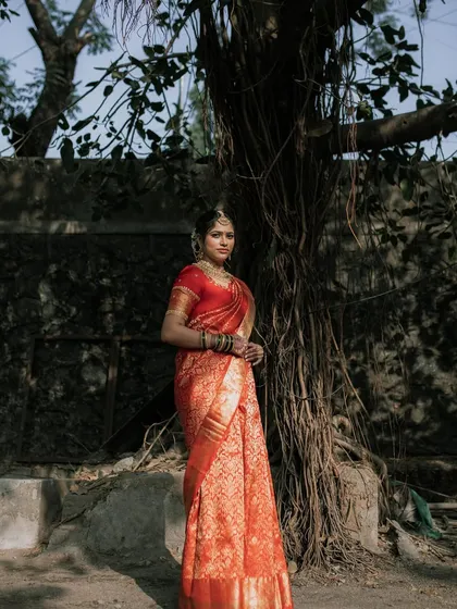 A full-length shot capturing the grandeur of the red bridal saree. The makeup is bold enough to match the occasion but still feels natural and true to her.