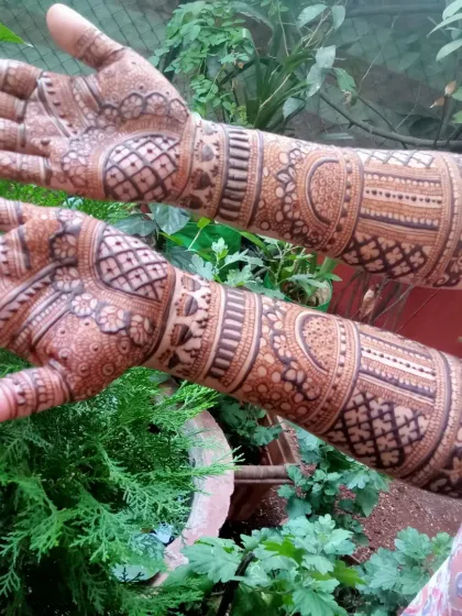 This full-coverage design showcases intricate geometric and floral patterns extending from the palms to the forearms, perfect for a traditional bridal look.