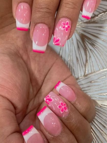 A cute twist on a French manicure, with bright pink tips and floral art on the accent nails.