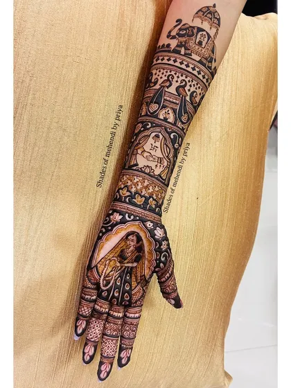 A full-arm bridal design featuring a bride in a doli on the palm. The arm is decorated with bands of traditional motifs, including elephants and peacocks.