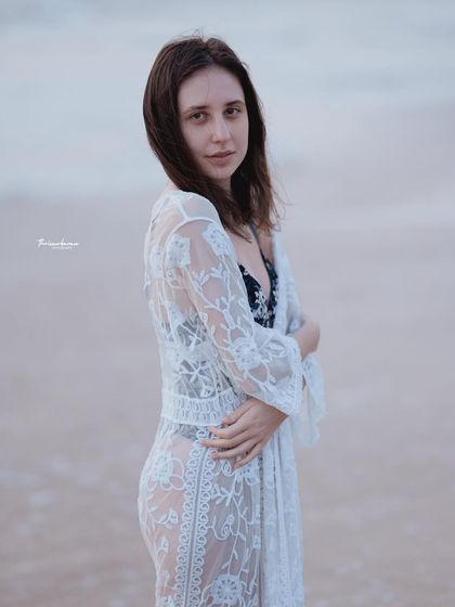 A three-quarter portrait against the soft light of the ocean. The simple composition and direct gaze make for a classic and beautiful beach photo.