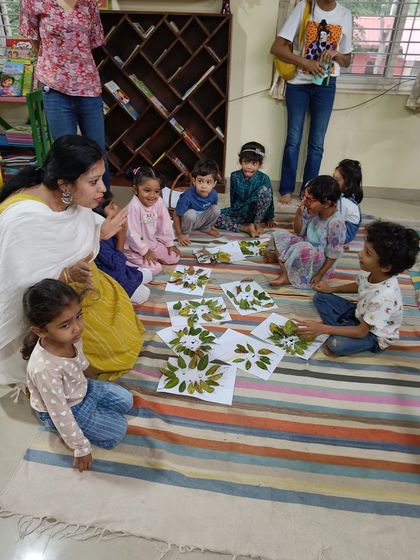 A storyteller helps the children arrange their finished leaf crafts for a group photo.