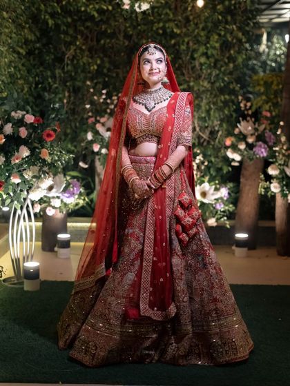 A full-length bridal portrait in a beautifully lit garden setting at night, showcasing her entire stunning ensemble.