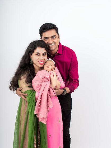 A beautiful studio portrait of a new family. The parents' colorful outfits contrast beautifully with the simple white background, creating a vibrant image.