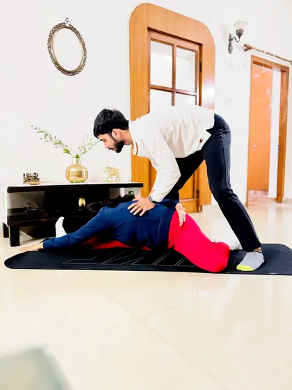 Applying gentle pressure in Pigeon Pose to help the student release tension in her hips and deepen the forward fold.
