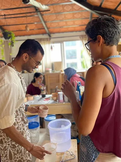 A candid moment of conversation and learning during a glazing session, where students get to see their pieces come to life with color.