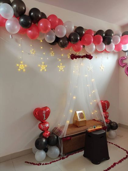 This is another view of the romantic canopy decoration, showing the 'I love you' heart-shaped balloons and the gift placed centrally under the lit-up canopy.