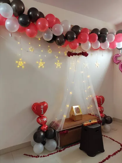 This is another view of the romantic canopy decoration, showing the 'I love you' heart-shaped balloons and the gift placed centrally under the lit-up canopy.