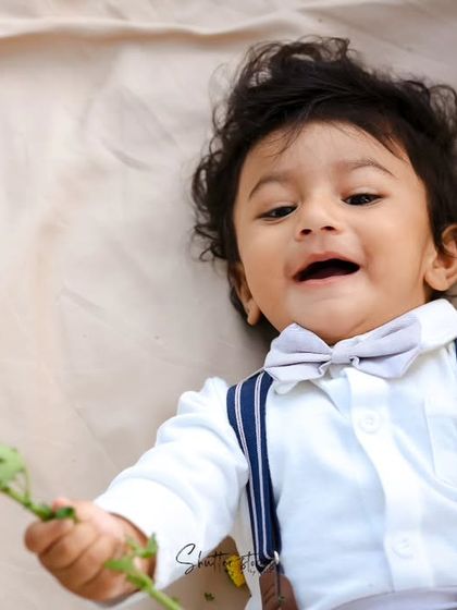 A fun, candid shot of the toddler lying down and playing with flowers.