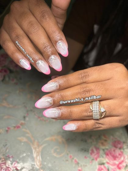 A playful twist on a French manicure with bright pink tips and a touch of silver glitter on a frosted base. It's a fun and chic look, perfect for summer.