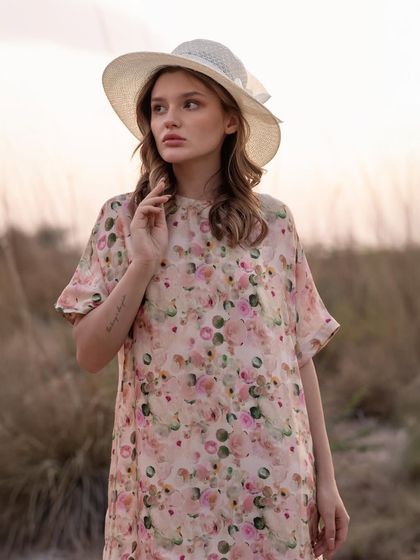 A beautiful portrait showcasing a floral print dress and a summer hat. The soft focus on the background keeps the attention on the model and the delicate details of her outfit.