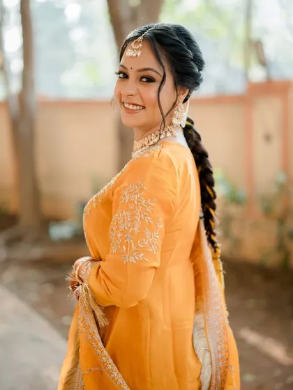 A beautiful Punjabi bride ready for her ceremony. This look features a classic winged eyeliner, a neat updo with a maang tikka, and a radiant smile.