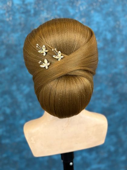 A sleek and clean bun with a twisted overlay, adorned with delicate butterfly pins.