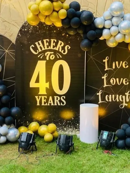 A bold and stylish 40th birthday celebration. This outdoor setup features a 'Cheers to 40 Years' backdrop, framed by a black, yellow, and silver balloon arch.