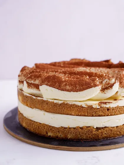 A close-up of our classic Tiramisu Cake, showing the distinct layers and the generous dusting of cocoa powder on top.