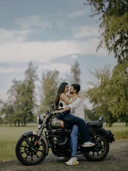 A classic romantic pose on a Royal Enfield. This shot from their pre-wedding session is both adventurous and deeply romantic, set against a beautiful natural backdrop.