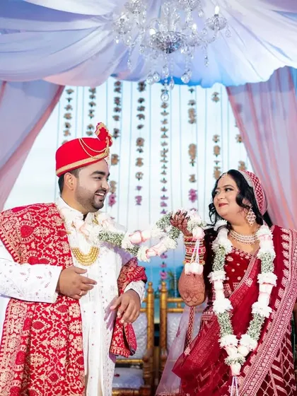 The playful Varmala exchange under a beautiful mandap with a chandelier, overlooking the sea.