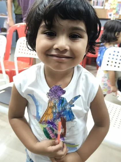 The joy on this little girl's face says it all. She has just finished coloring her own puppet after watching the Chitrakathi show, a perfect hands-on activity to make the cultural experience even more memorable.