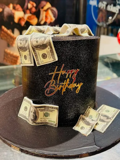 A stylish black sparkle cake decorated with edible dollar bills for a simple yet striking money-themed design.