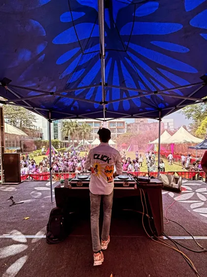 Another perspective of the massive UCB Holi event, showing the huge outdoor setup under a blue tent.
