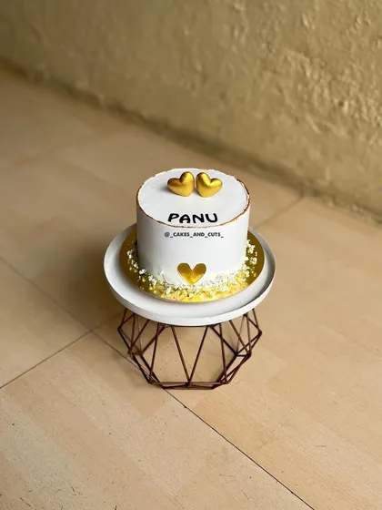 An aesthetic love-themed cake with golden hearts, simple and elegant.