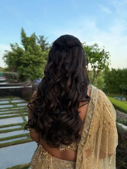 A simple and elegant half-up twist with soft, natural-looking waves, perfect for an outdoor engagement or reception.