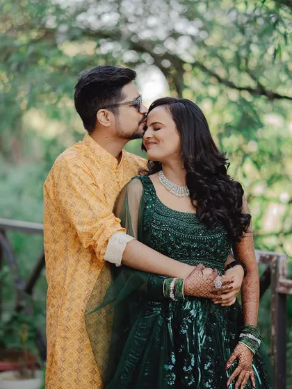 A tender moment with a forehead kiss, set against a soft green background. This classic pose is all about warmth, affection, and the promise of forever.