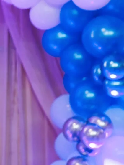 Another perspective of the blue and silver balloon decor against a soft purple curtain, capturing the party's color scheme.