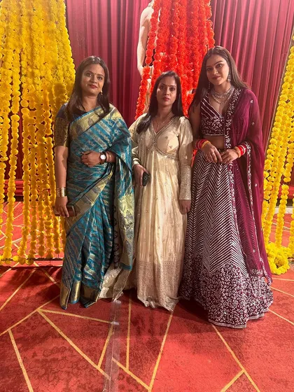 A group of happy clients at a wedding, all dressed in my custom creations, including a saree, a gown, and a lehenga.