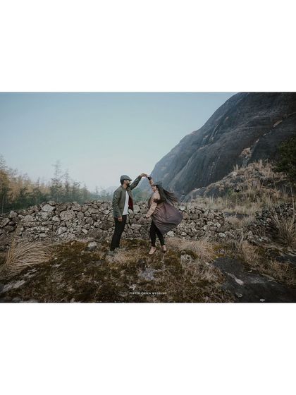 Ananthu and Sarga dancing together against a mountain backdrop. This wide shot captures their joy and the epic scale of their love story.