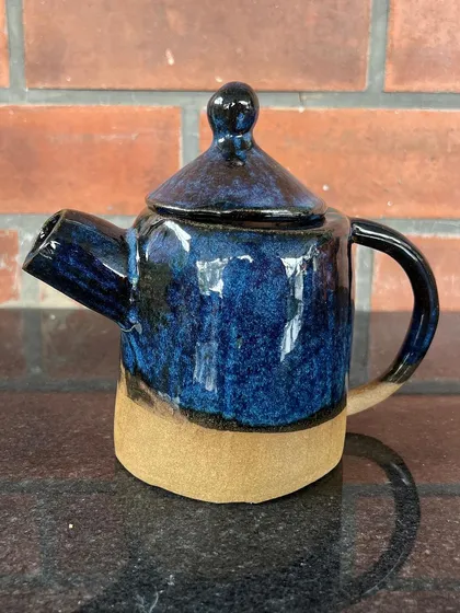 This wheel-thrown teapot has a gorgeous, deep blue glaze that breaks over the texture of the clay.