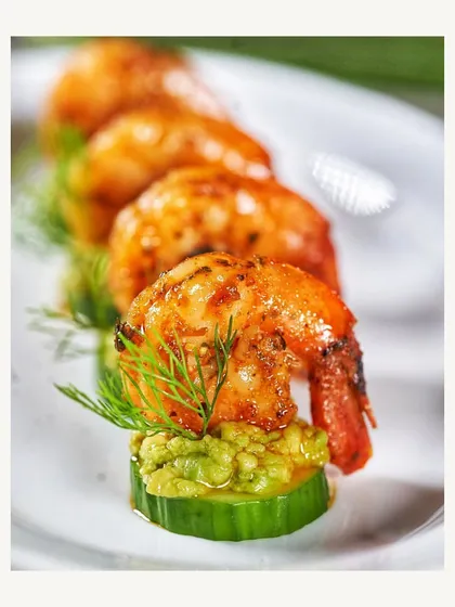 A beautifully plated Pesto Prawn skewer on a slice of cucumber. This appetizer is a perfect blend of fresh and savory flavors.