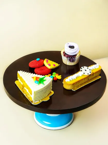A collection of colorful pastries arranged on a modern, two-toned cake stand.