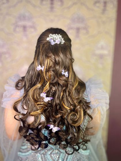 A whimsical "baby doll" hairstyle for our bride. I created soft curls and adorned them with delicate butterfly clips for a playful and romantic look.