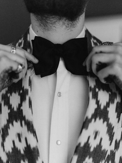 A close-up on the groom's bow tie. This black and white detail shot captures the texture and classic style of his getting-ready process, a nod to timeless elegance.