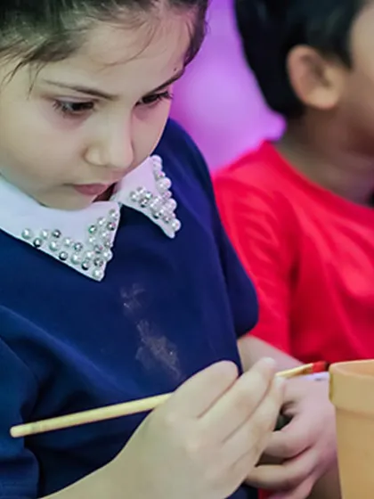 Another focused artist decorating a small pot. These activities are perfect for creating a calmer zone within a high-energy party.
