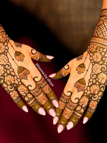This design blends a floral vine with a geometric grid pattern on the back of the hand. The hanging jhumkas add a playful, traditional touch to the modern layout.
