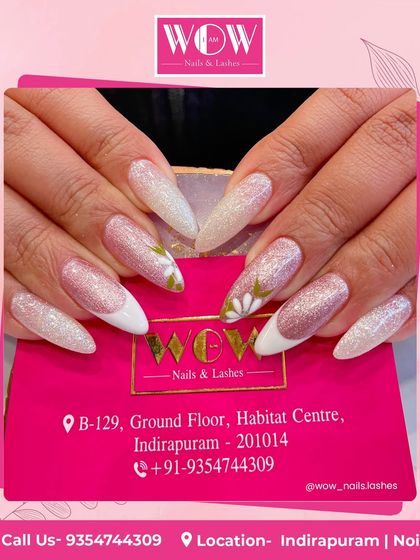 These long, stiletto extensions are a work of art, featuring a glittery pink and white ombré base with delicate white floral details. A beautiful and feminine choice.