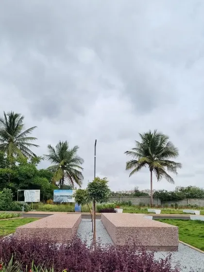 A view of the community space taking shape, with long concrete benches and newly planted grasses. The design uses simple, modern forms for the hardscaping, allowing the plants to be the main feature.