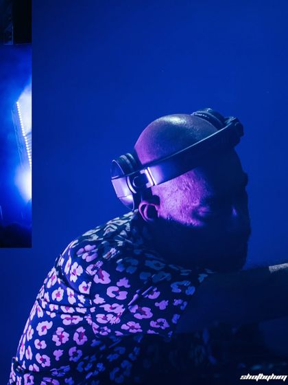 A moody, blue-lit close-up of Nucleya, focused on his headphones and the side of his face.