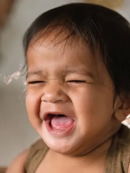 Sometimes the most expressive faces make for the best photos. This candid shot captures a baby's big, joyful laugh, showcasing the real, unposed moments that reveal their budding personality.