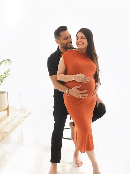 A joyful and candid moment. The couple's smiles show their excitement and happiness, captured in a simple, clean studio setting that keeps the focus on their emotion.