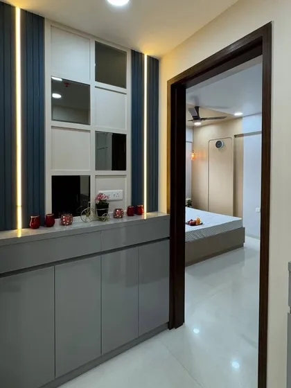 This entryway unit combines glossy grey cabinets with a dark blue and white paneled wall. The integrated lighting adds a modern touch and highlights the different textures.