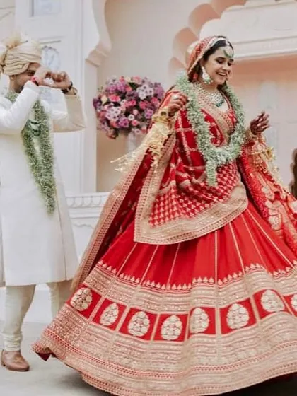 A candid moment captured in a classic red and gold bridal lehenga. The design on the skirt border is traditional, making it a perfect choice for pheras and other wedding rituals.