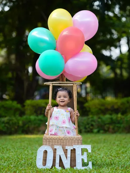 A happy smile from inside the hot-air balloon basket. This classic prop always brings out the joy in children during their first birthday photoshoots.