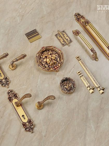 The Amyra Collection offers a complete suite of ornamental hardware. This image shows lever handles, cabinet pulls, and a magnificent lion-head door knocker, all unified by a classic design language and Royal Gold finish.