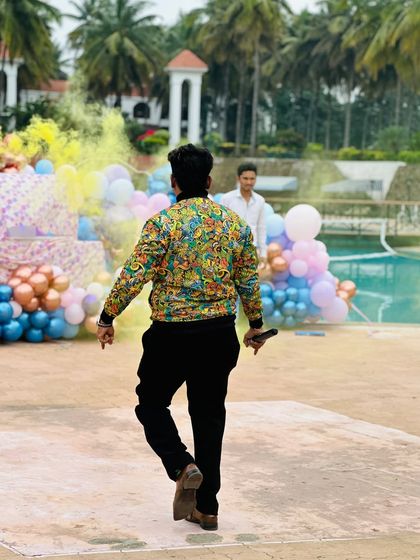Walking towards the stage at a pool party, ready to kick things off. The colorful decor and outdoor setting create a perfect backdrop for a day of fun.